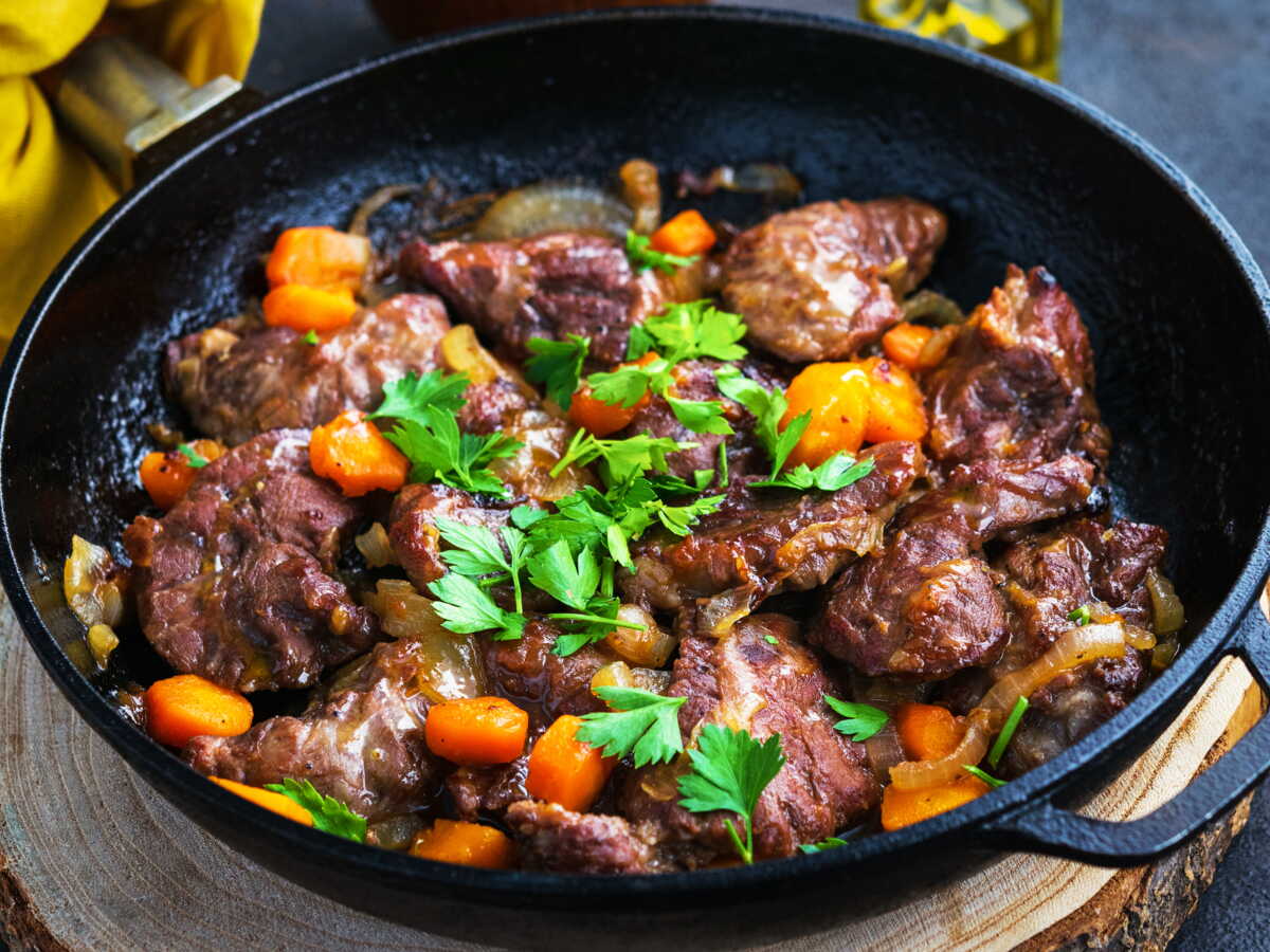 Joues de porc mijotées façon grand-mère dans une cocotte en fonte avec carottes et sauce au vin