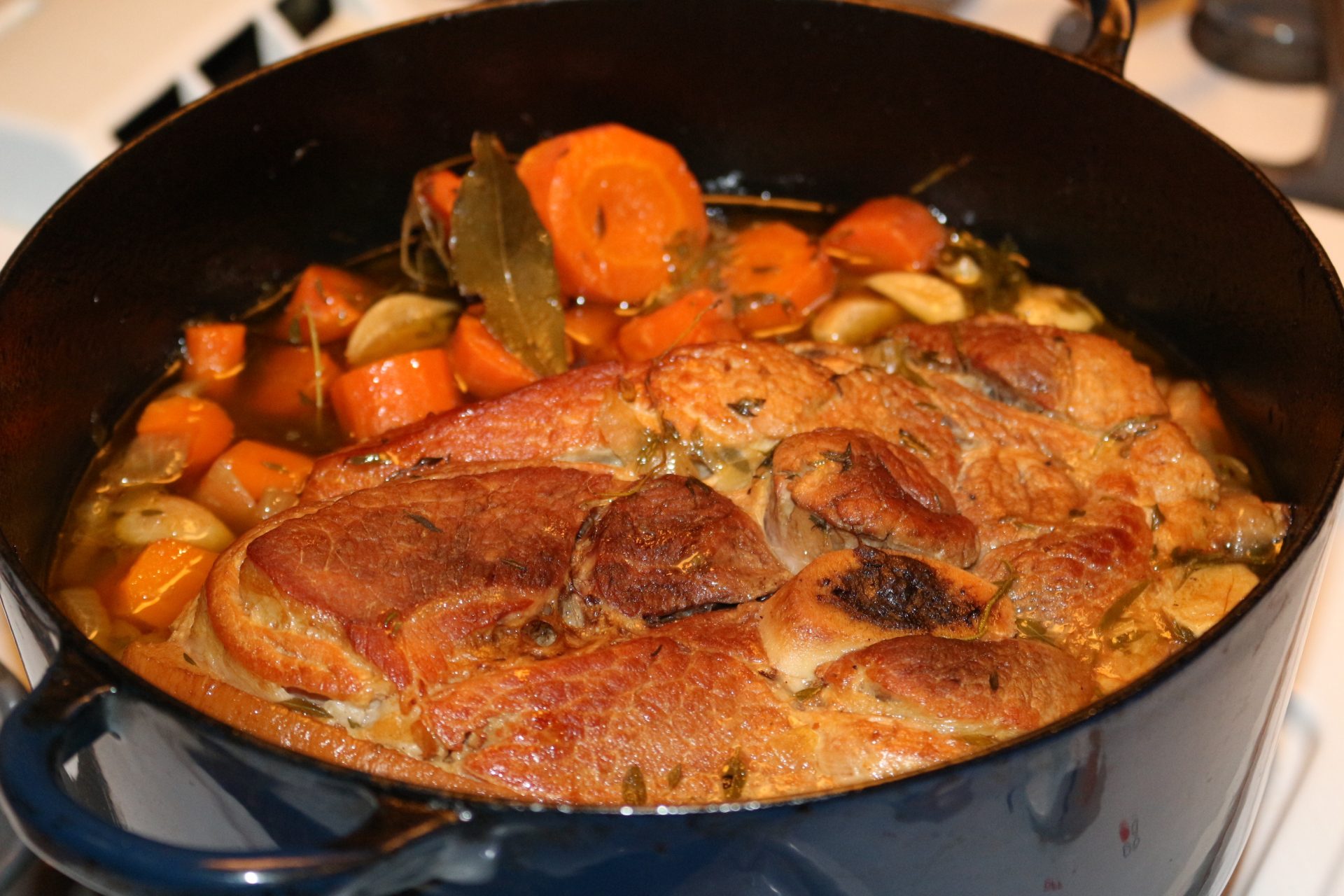 Rouelle de porc dorée et mijotée dans une cocotte avec oignons et carottes
